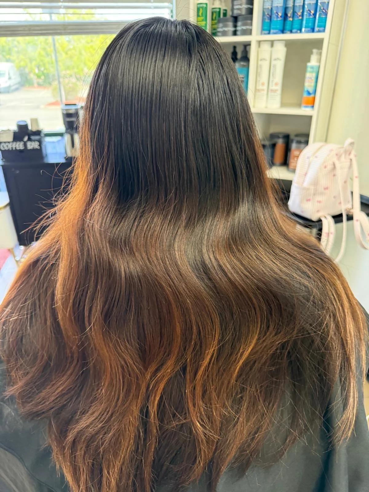A warm caramel balayage melted through long dark hair