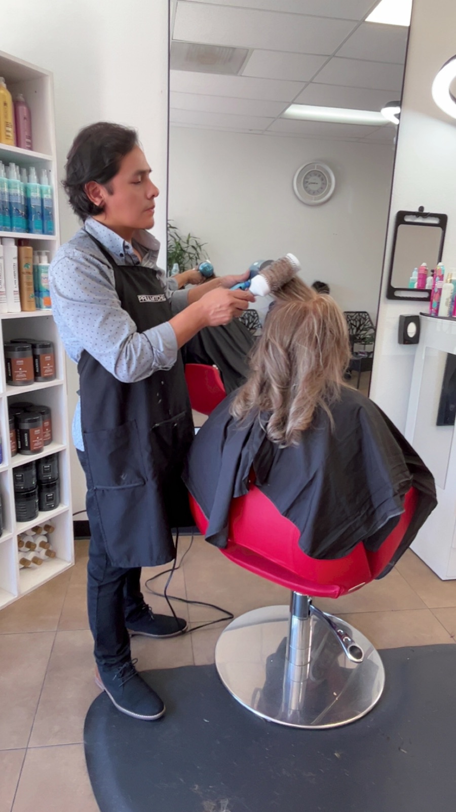 A stylist blow drying and finishing a client inside the salon